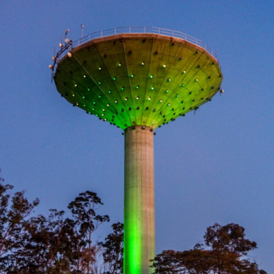 A water tower lit up from underneath in green lights
