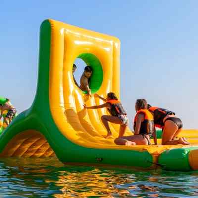 Children playing on a yellow inflatable water obstacle course