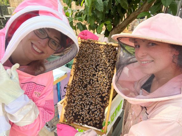 Two beekeepers smiling with a bee hive sheet