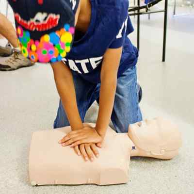 A child doing CPR on a mannequin