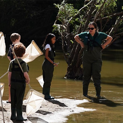 Guide and kids at waterway with nets