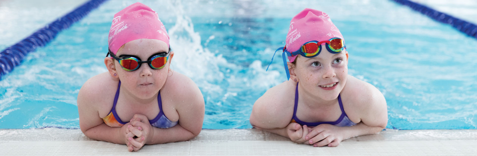 Two children lean on the edge of the pool and kick the pool water