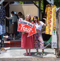 A woman standing with another woman holding a Garage Sale Trail sign