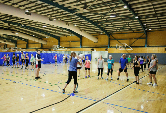 Group of people doing exercise in an indoor arena.