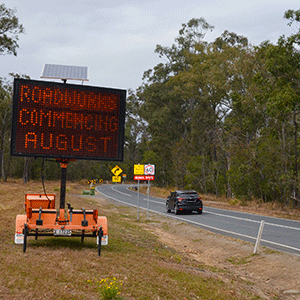 Sign alerting people that roadworks are starting with a car driving on a road