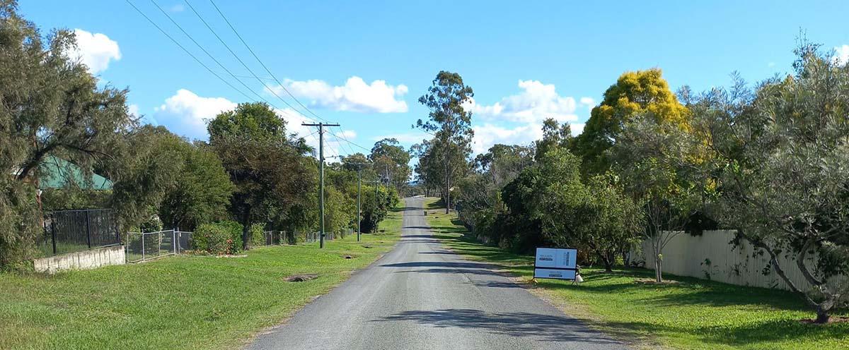 Section of Jimboomba Road surrounded by tall trees