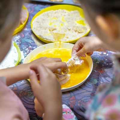 Two children decorate biscuits sitting on a yellow plate