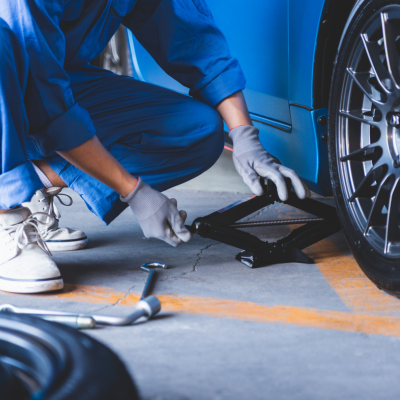 Person in mechanic wear works by a car tyre