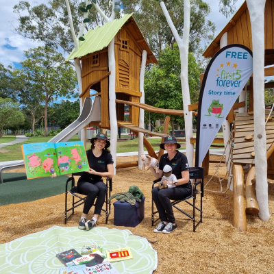 Two adults in the park showing their story books