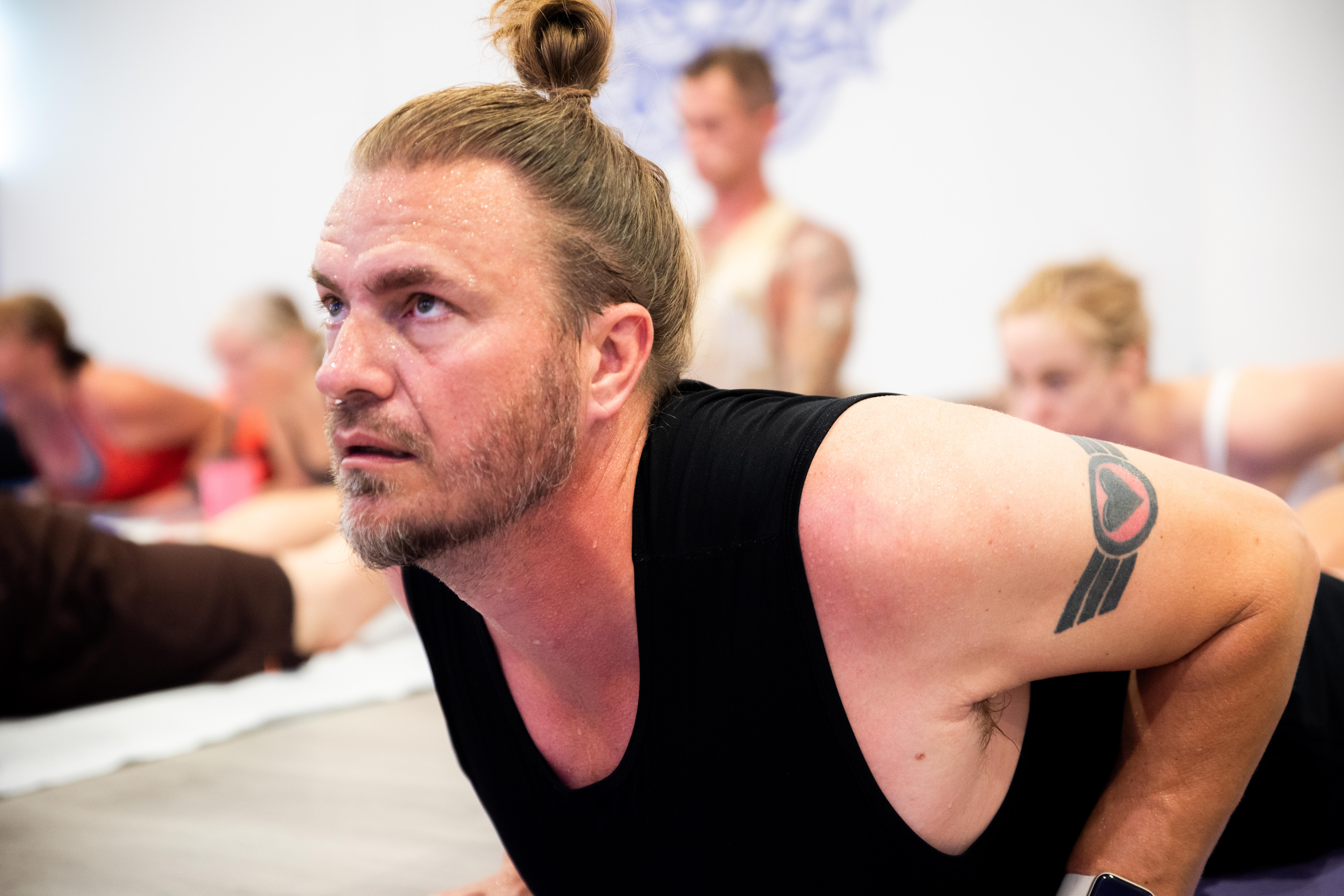 A man stretching in a hot yoga class with other participants
