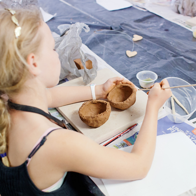Young girl creating clay bowls