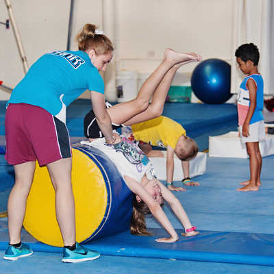 Young children doing gymnastics with adult helper
