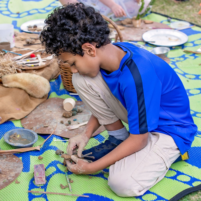 A boy playing with different types of natural mediums to create craft