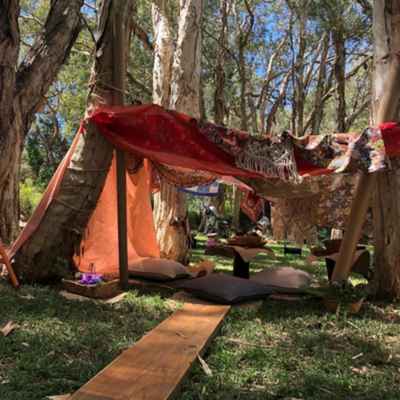 Play tents and natural play equipment set up among trees