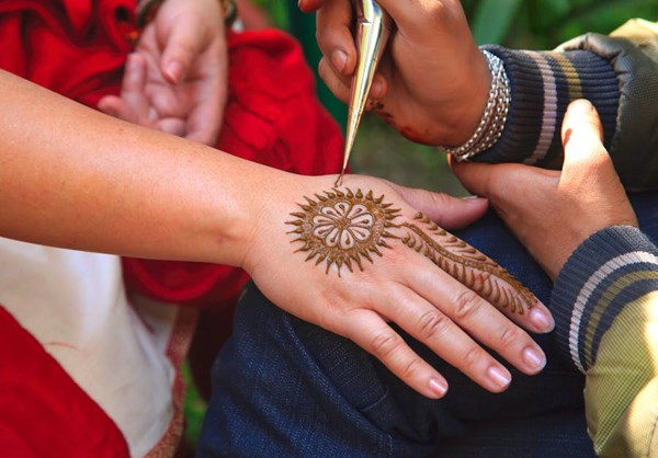 Hand being held out while someone paints a Henna drawing on it