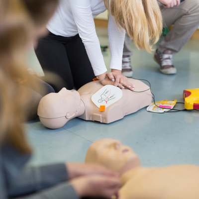 Teen doing chest compressions on a dummy as part of CPR