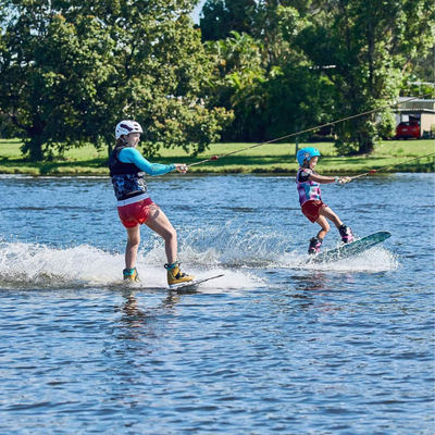 Two children wakeboard side by side