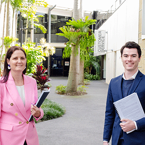 Man and woman stand in front of council building with documents in hand