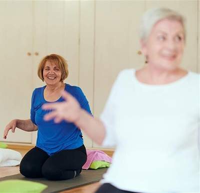 Two women with their arms in the air doing a yoga pose.